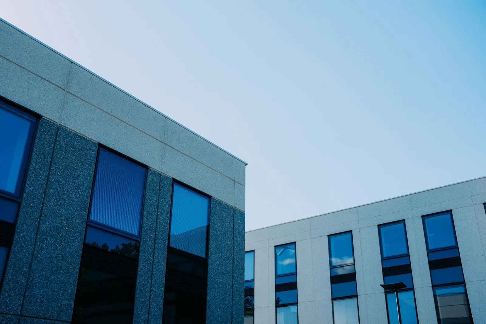 From below of contemporary office buildings with reflection in windows located in city. Stock photo illustrating Ganesh Housing's earning call story.