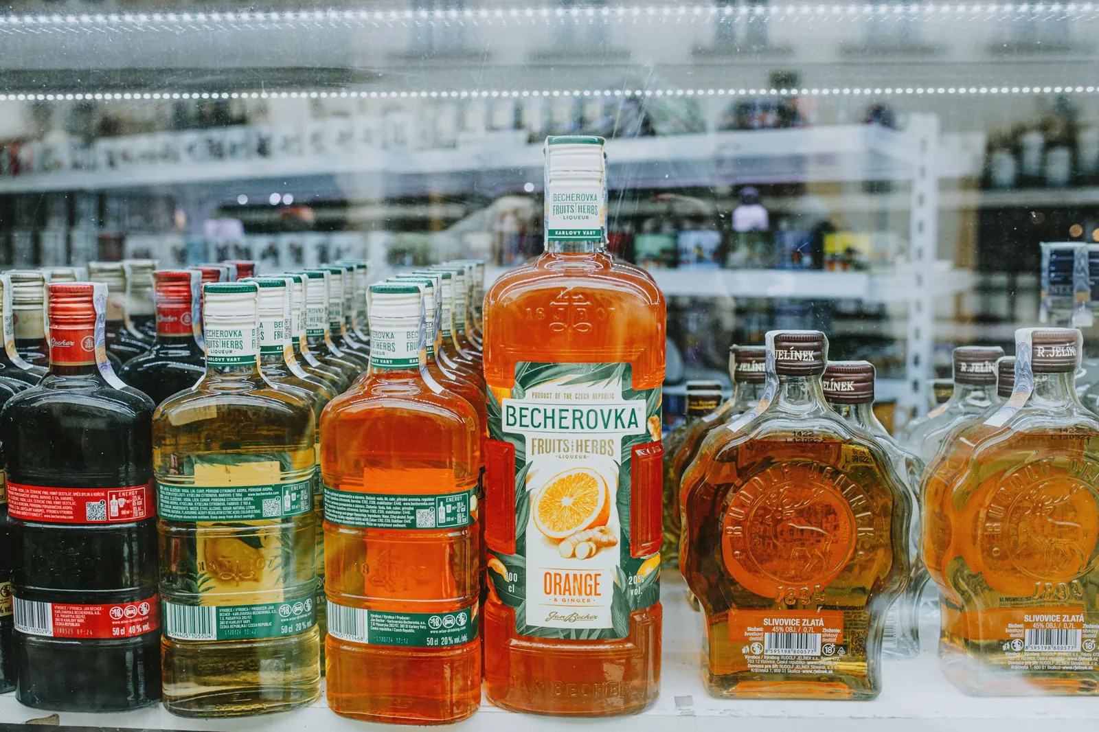 An array of vibrant liquor bottles displayed in a store showcase highlighting various spirits. Stock photo illustrating Allied Blenders and Distillers' expansion story.
