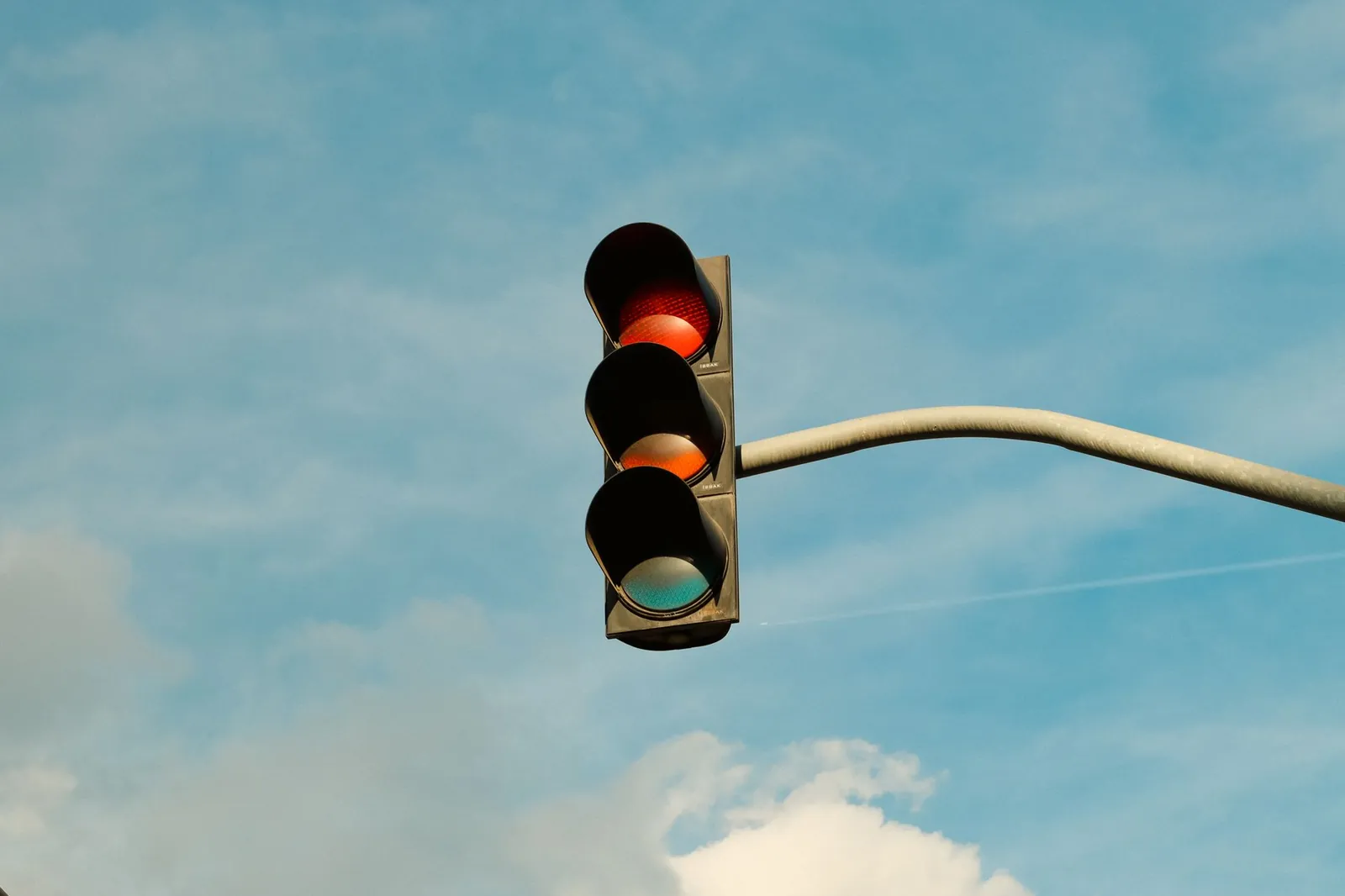 A traffic light with red signal set against a blue sky, signifying stop in urban streets. Stock photo for the ALFA News guide: How to Use a Promoter Buying Signal for Indian Stock Research.