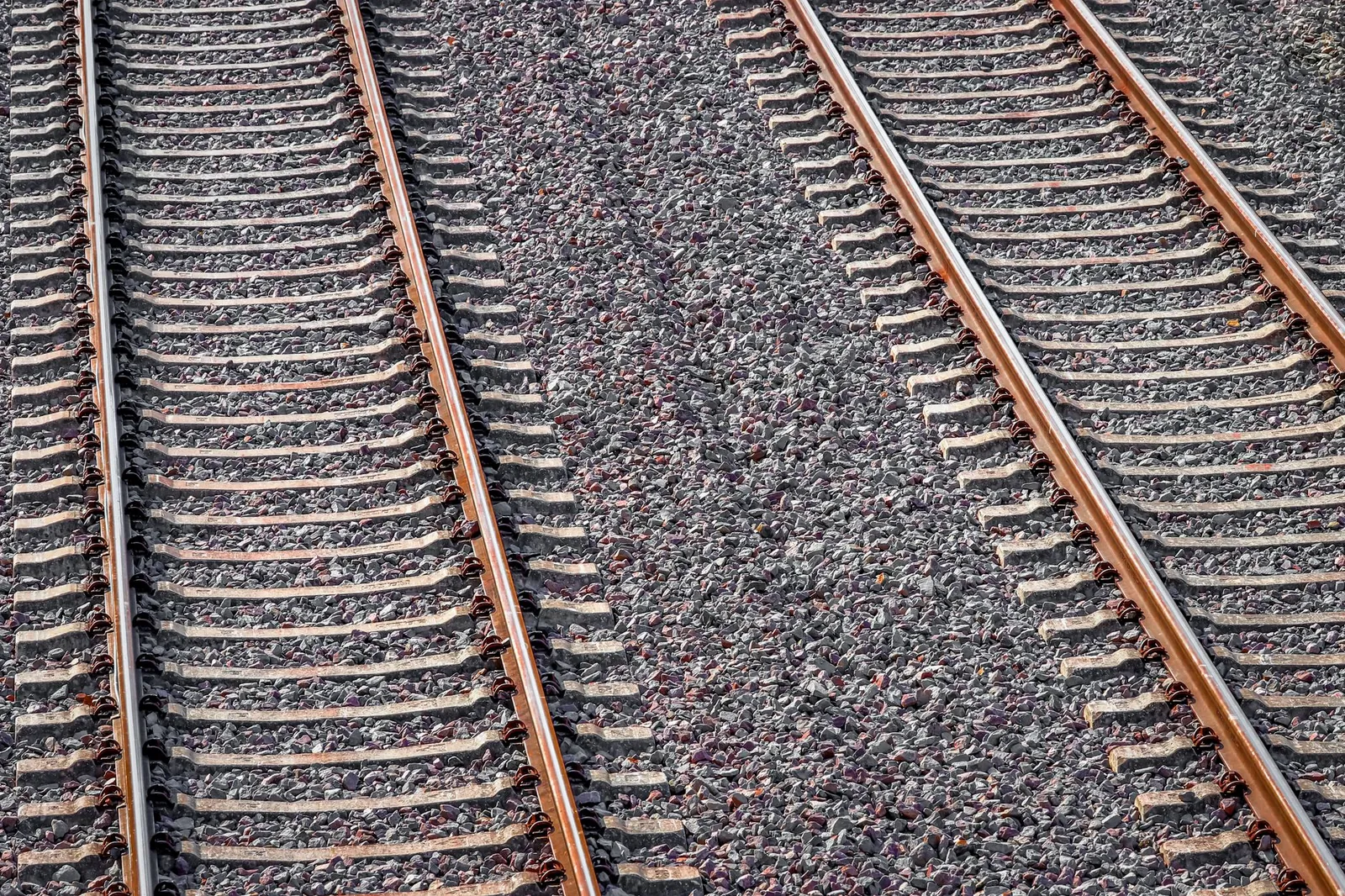 Two parallel railway tracks with rusty appearance captured under bright sunlight. Stock photo illustrating Ameenji Rubber's new order story.