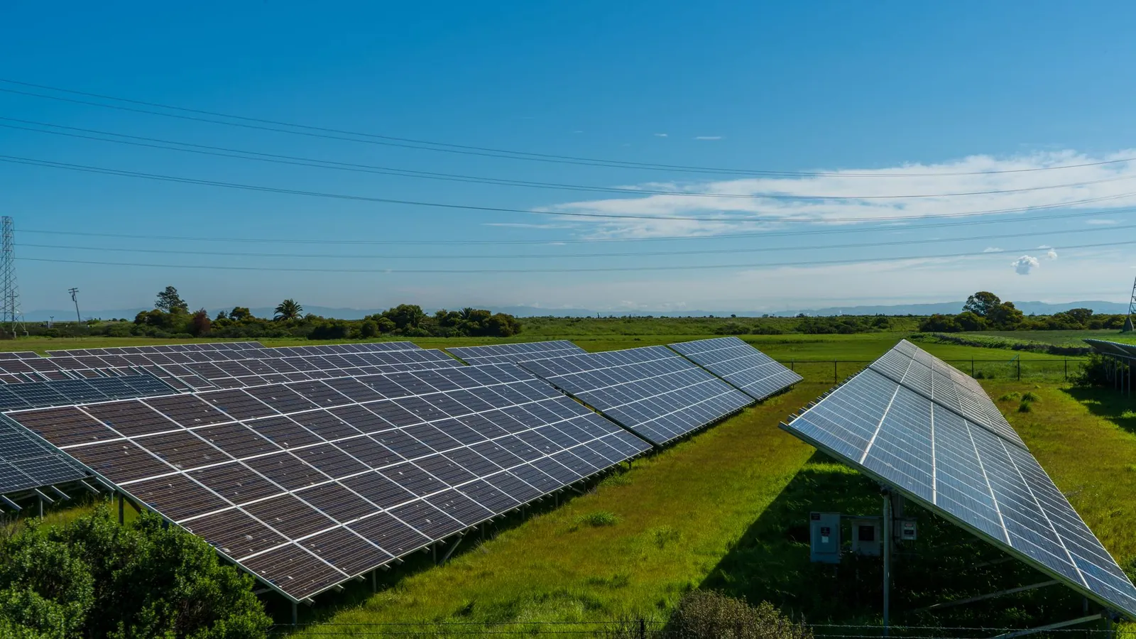 Solar panels in a lush rural field, generating renewable energy in San Rafael, CA. Stock photo illustrating SJVN's production started story.