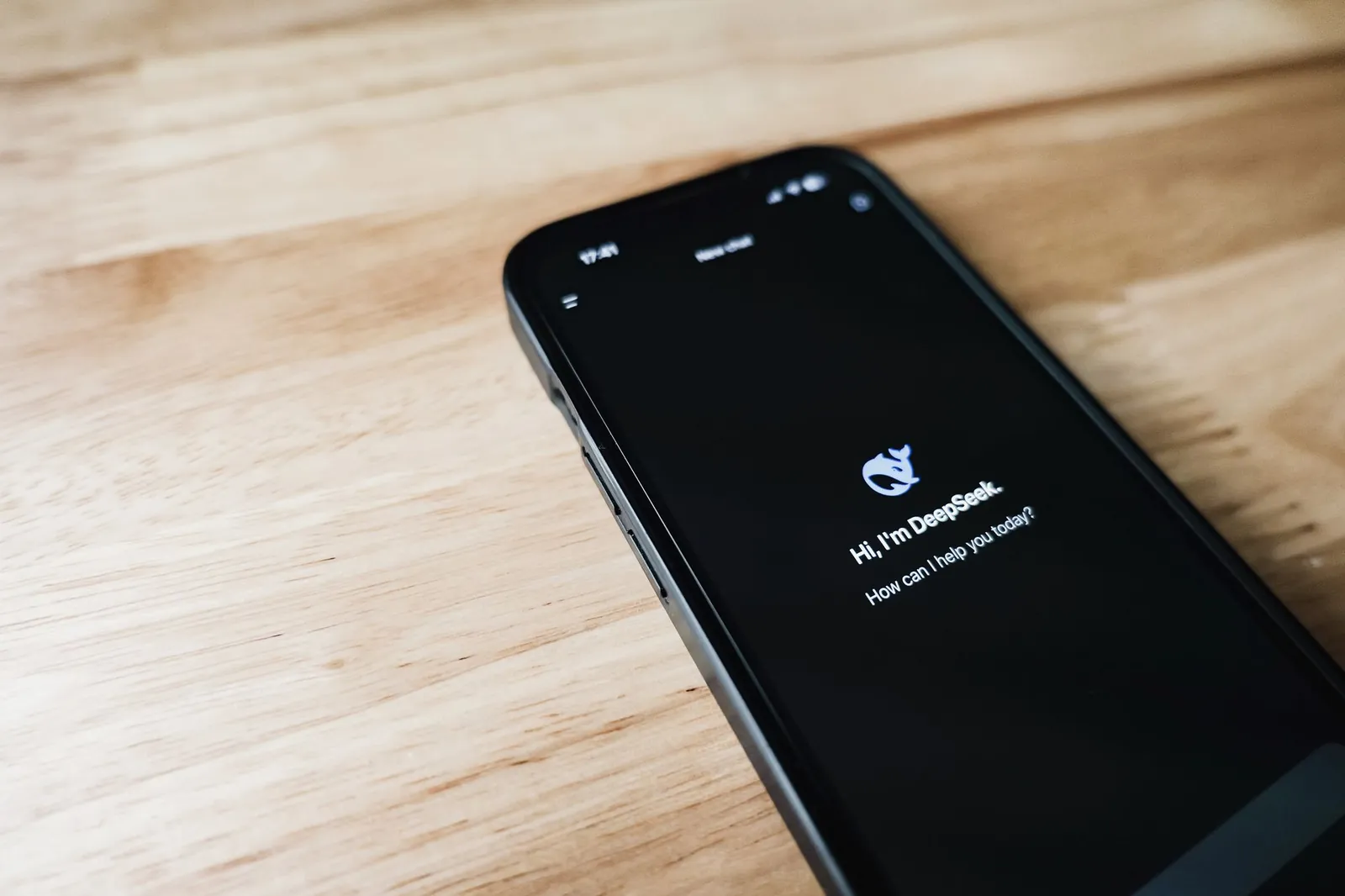 Close-up of a smartphone with DeepSeek virtual assistant on screen, placed on a wooden surface. Stock photo illustrating Le Travenues Technology's product launched story.