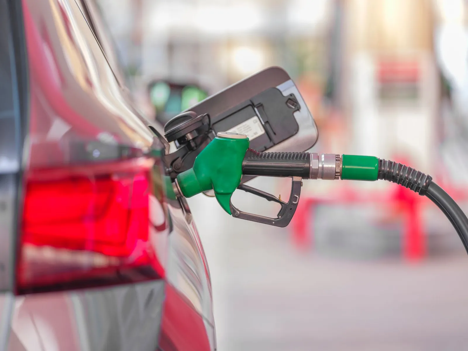 A close-up view of a fuel pump nozzle inserted into a car's tank at a gas station. Stock photo illustrating Maruti Suzuki India's product launched story.