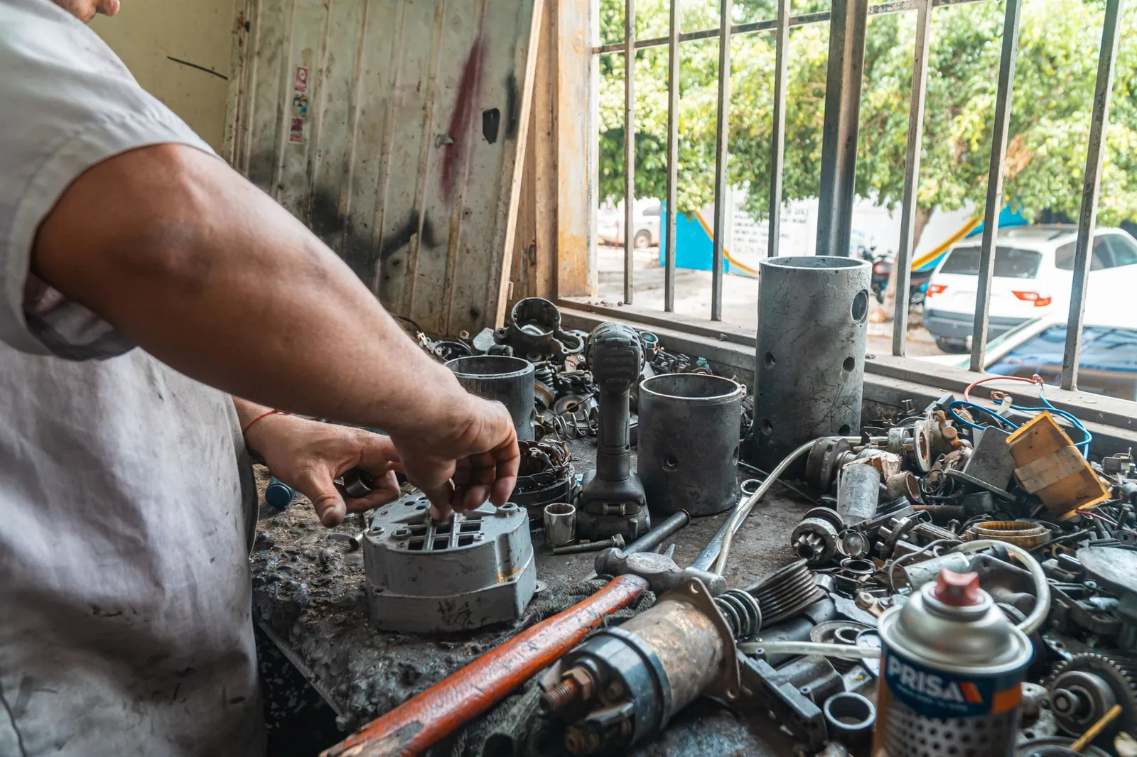 Close-up of a mechanic's hands working with car parts on a workshop table. Stock photo illustrating Rico Auto Industries' earning call story.