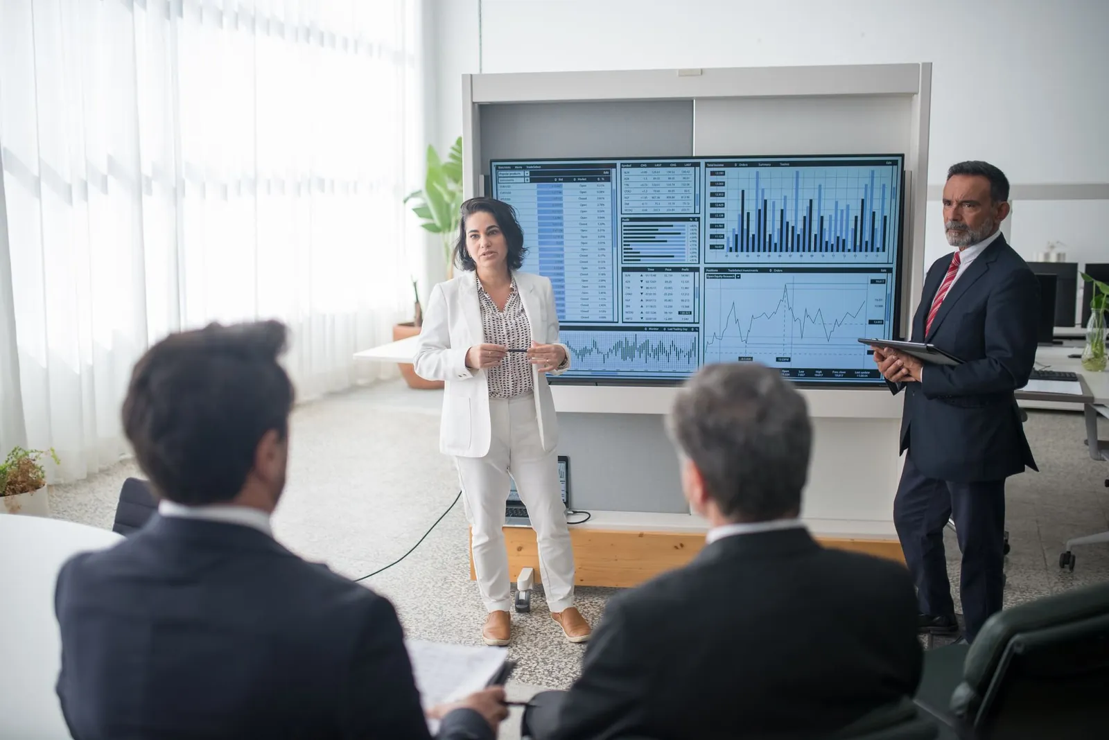 Colleagues discussing financial charts during a corporate meeting in a modern office. Stock photo illustrating Satin Creditcare Network's fund raise story.